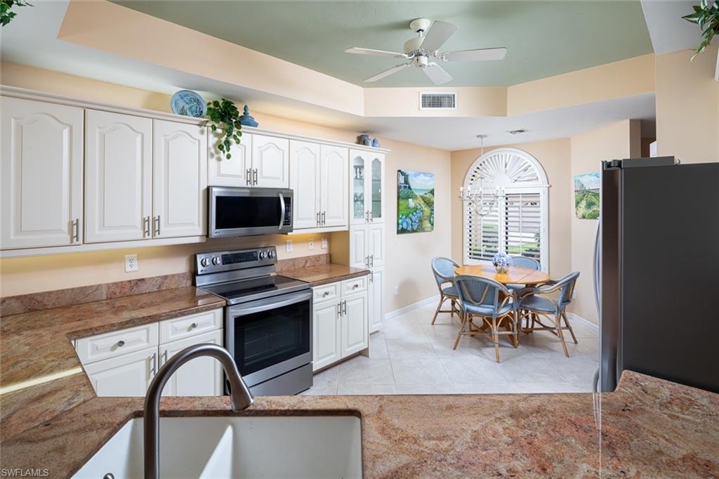 Kitchen featuring baseboards, stainless steel appliances, white cabinetry, and a sink