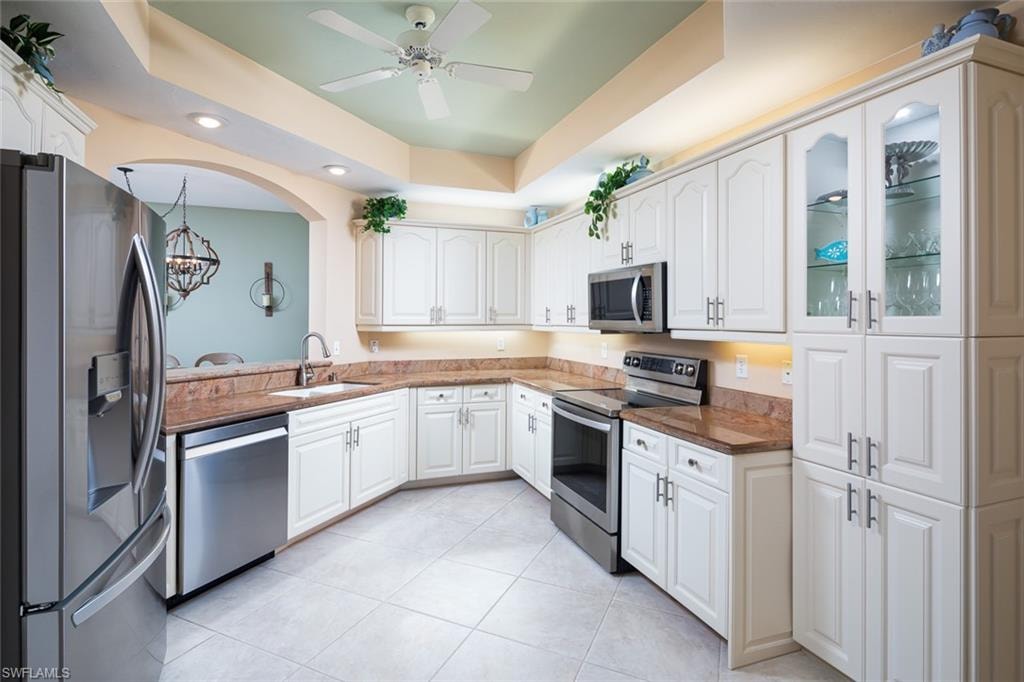 Kitchen with white cabinetry, light tile patterned floors, stainless steel appliances, and a sink