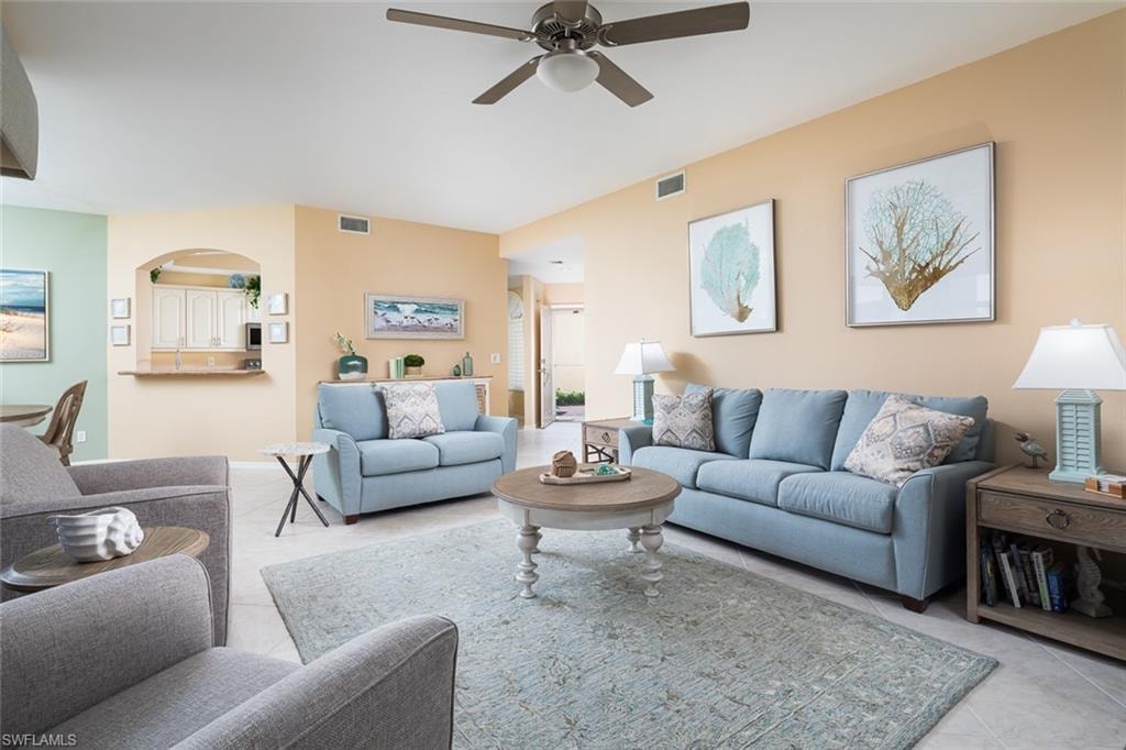 Tiled living area with visible vents, arched walkways, and ceiling fan