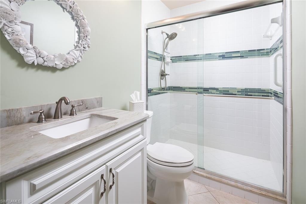 Bathroom with toilet, tile patterned floors, a shower stall, and vanity