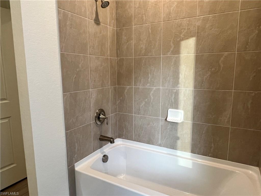 Bathroom with shower / tub combination and a textured wall