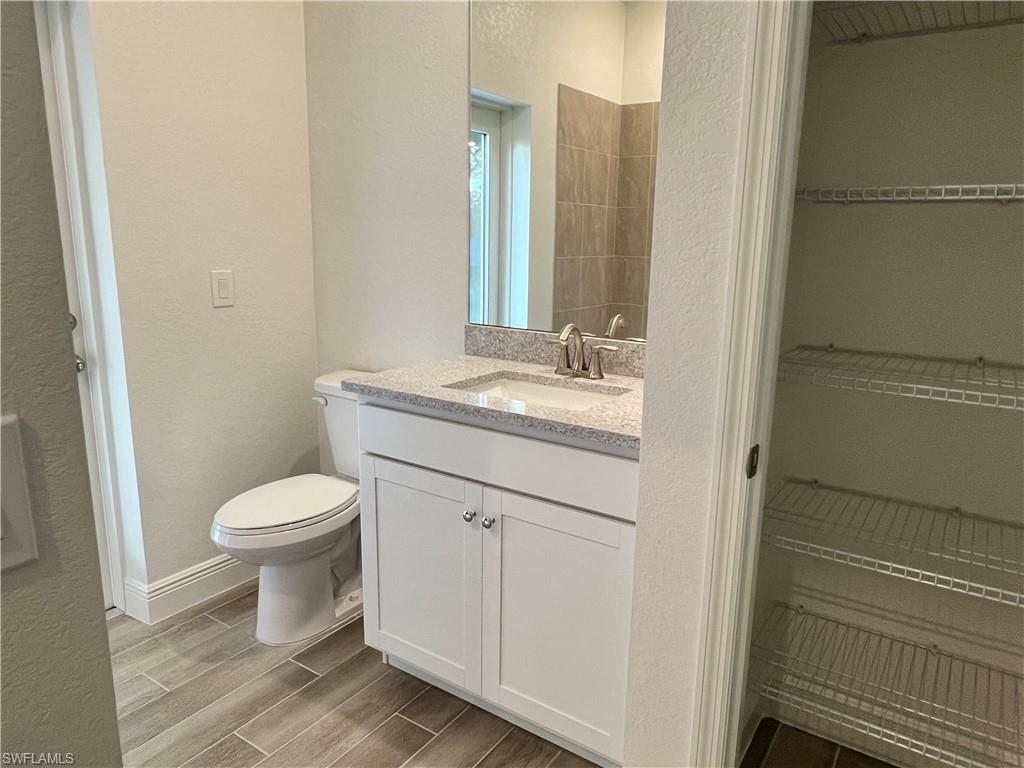 Bathroom with a textured wall, vanity, and wood finish floors