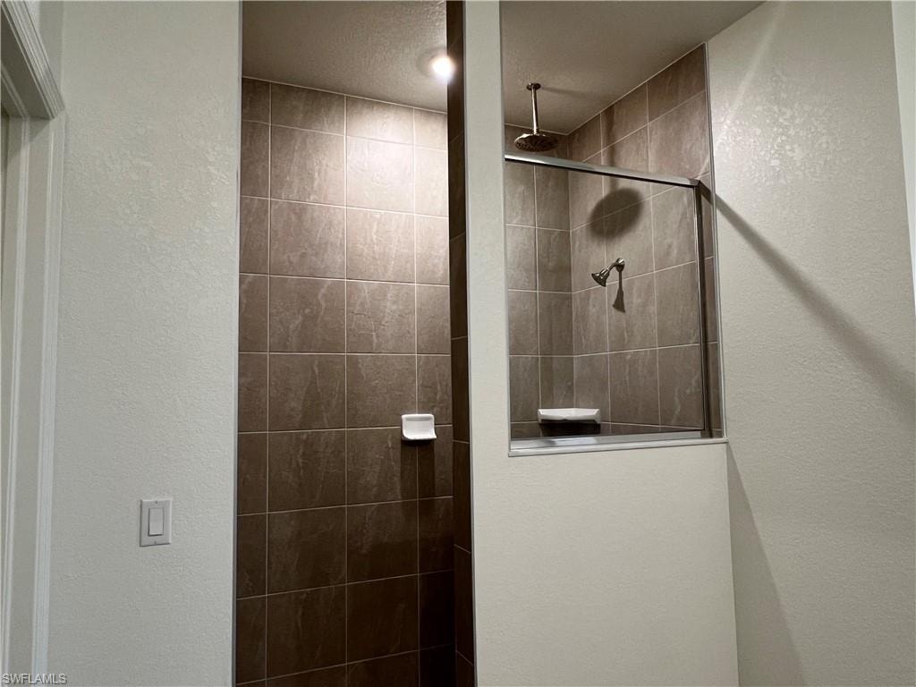 Full bath with a textured wall and a walk in shower