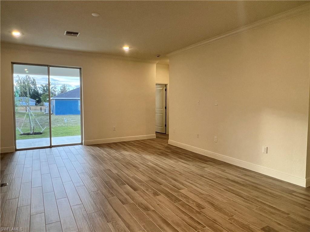 Empty room with crown molding, wood finished floors, and recessed lighting