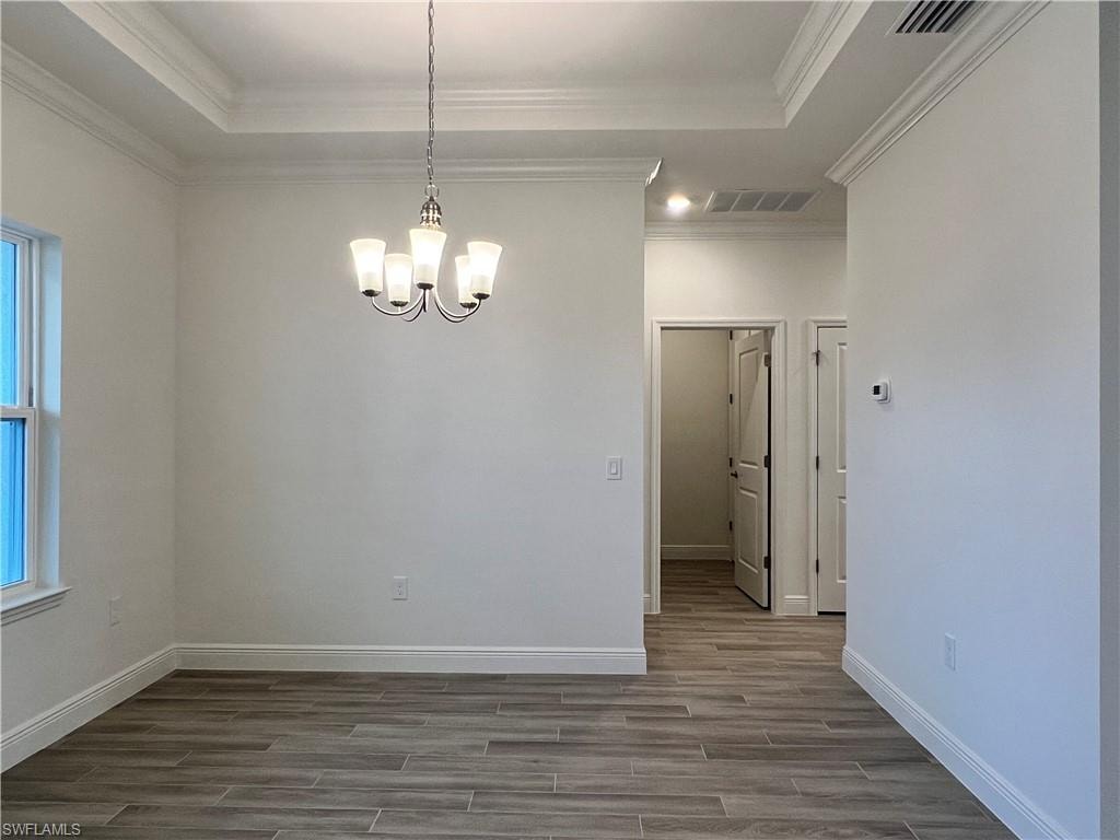 Unfurnished dining area with wood finish floors, a chandelier, and crown molding