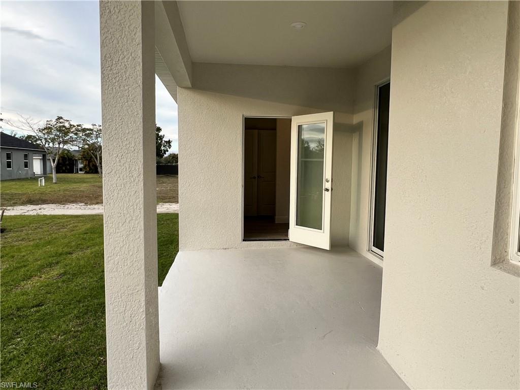 Entrance to property with stucco siding and a yard