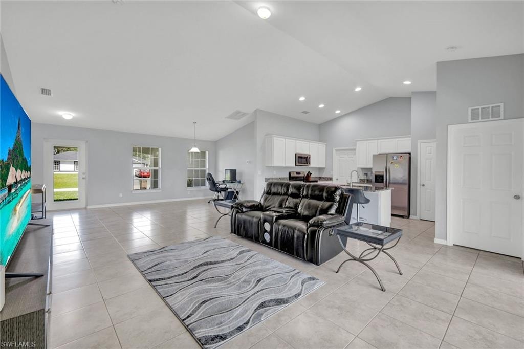 Living room featuring light tile patterned floors, high vaulted ceiling, and recessed lighting