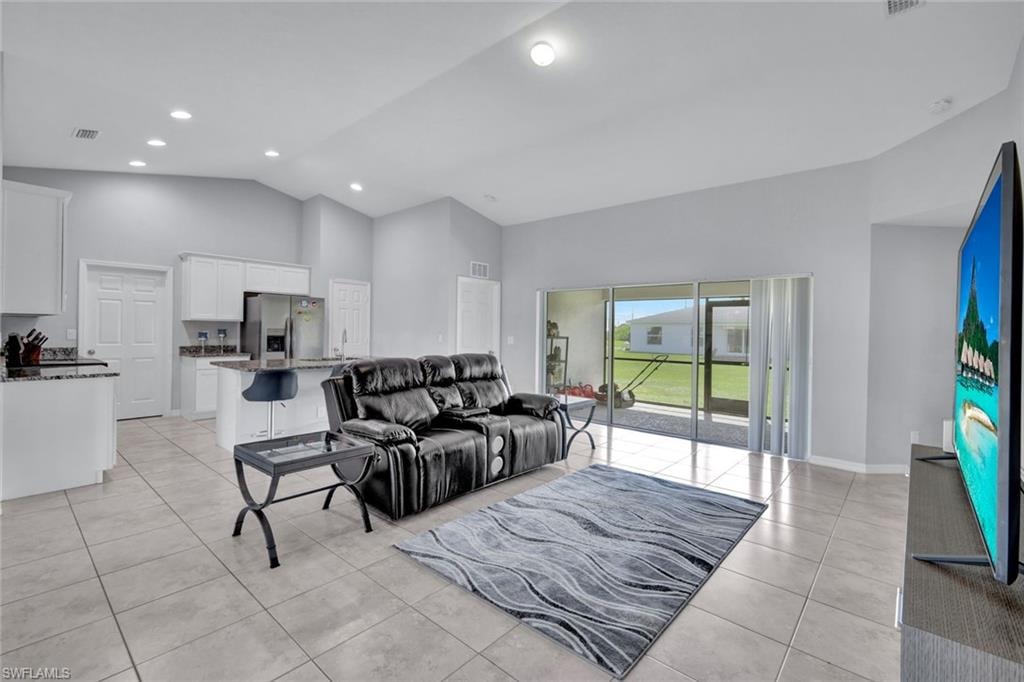 Living room with high vaulted ceiling, light tile patterned floors, and recessed lighting
