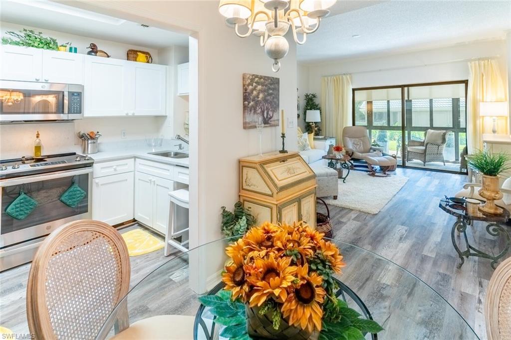 Kitchen with stainless steel appliances, vinyl wood-like flooring, a chandelier, and white cabinetry
