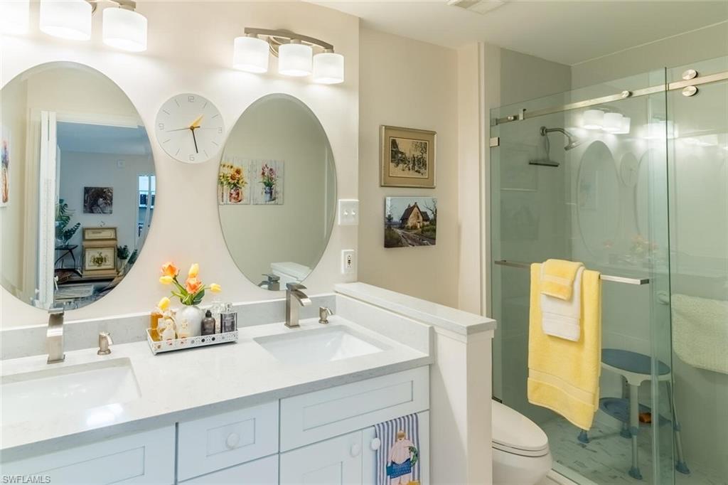 Bathroom featuring a shower stall and double vanity
