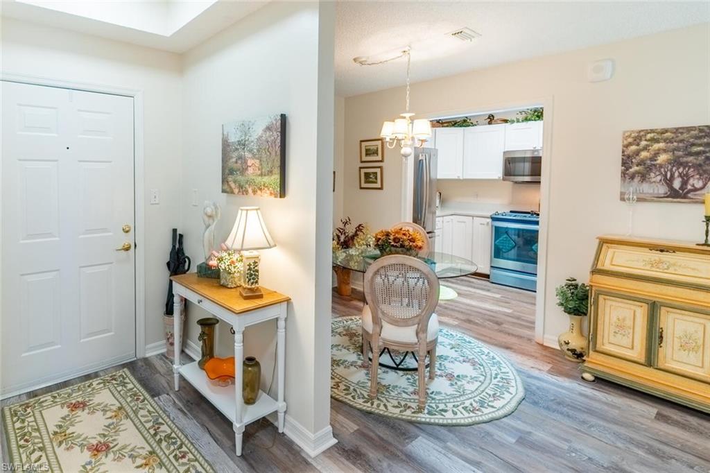 Foyer entrance with vinyl wood-like flooring and a chandelier