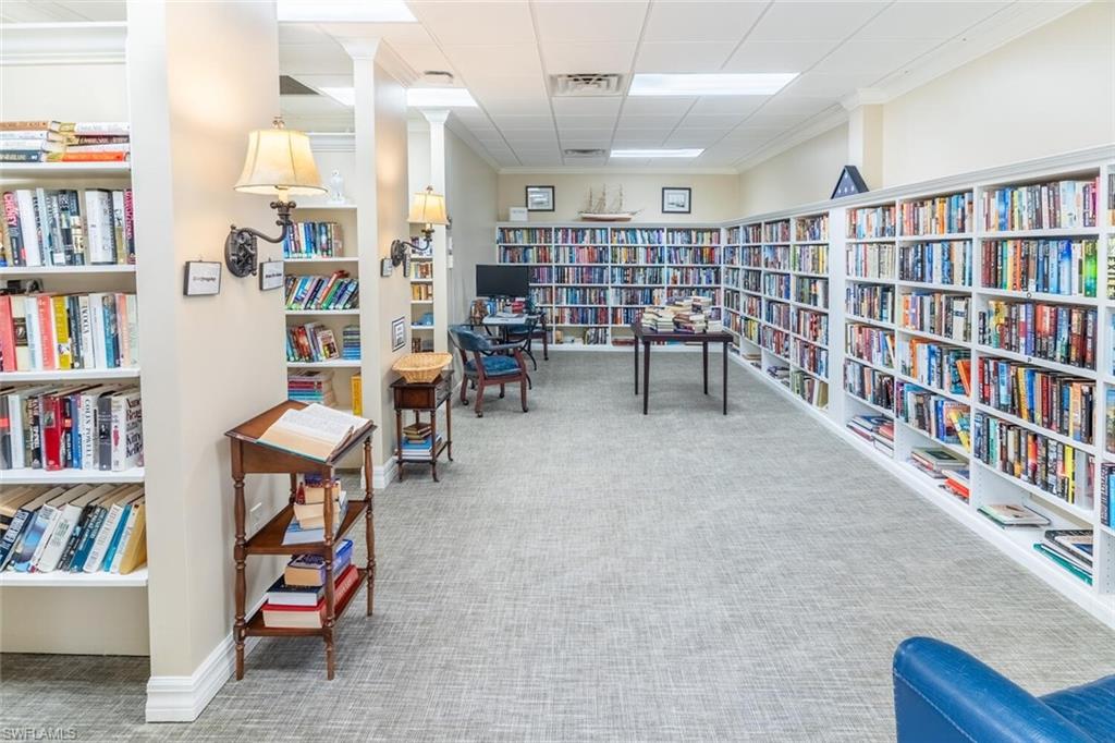 Sitting room with wall of books, ornamental molding, and a paneled ceiling