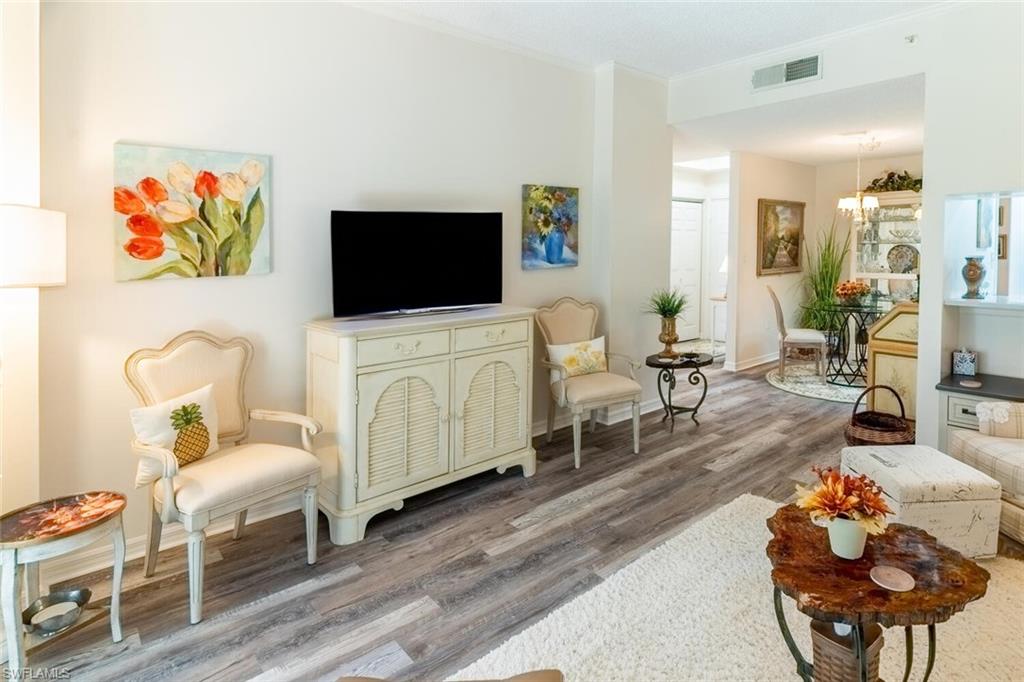 Living area with vinyl wood-like flooring and ornamental molding, and a chandelier