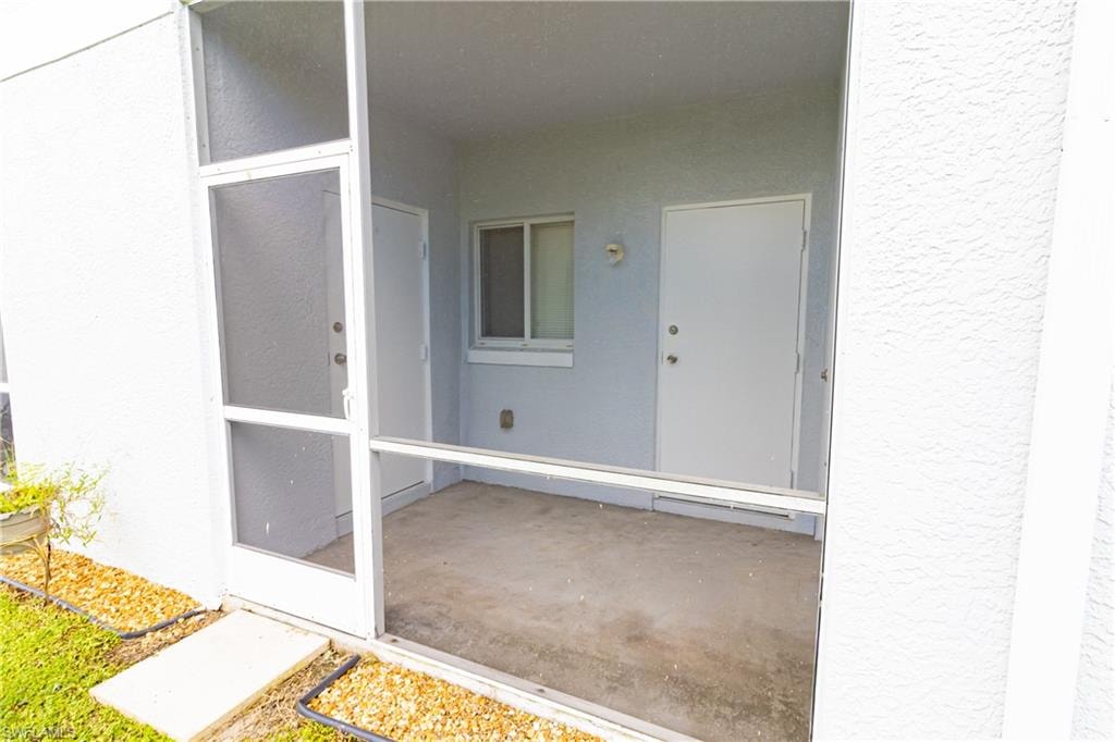 Property entrance with stucco siding and a sunroom