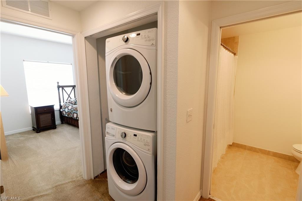 Laundry area featuring estacked washer and dryer and light colored carpet