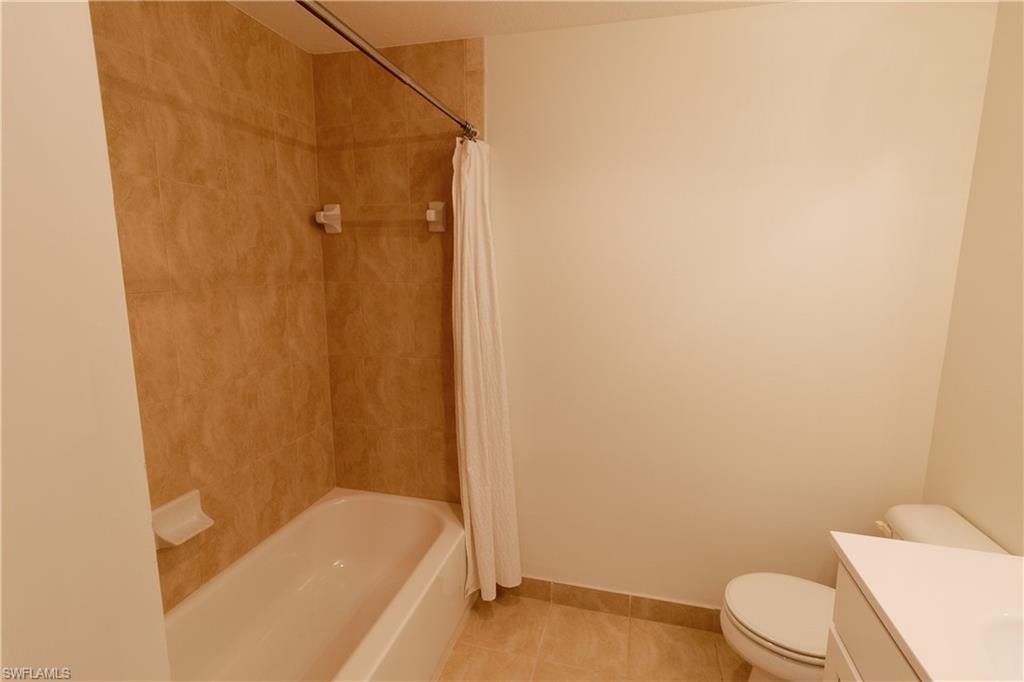 Bathroom with vanity, shower / bath combo with shower curtain, and light tile patterned flooring