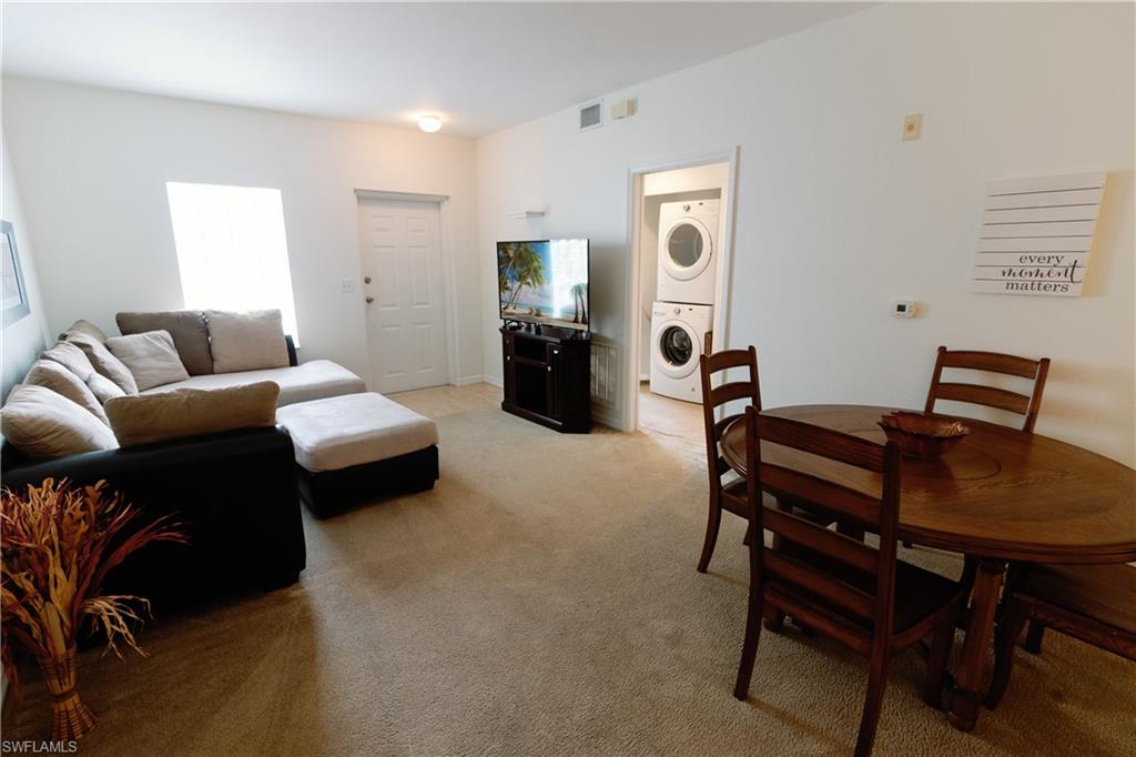 Living area with light colored carpet and estacked washer and dryer