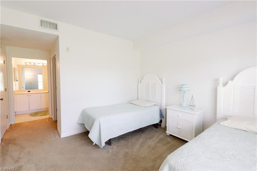 Bedroom featuring light carpet and ensuite bathroom