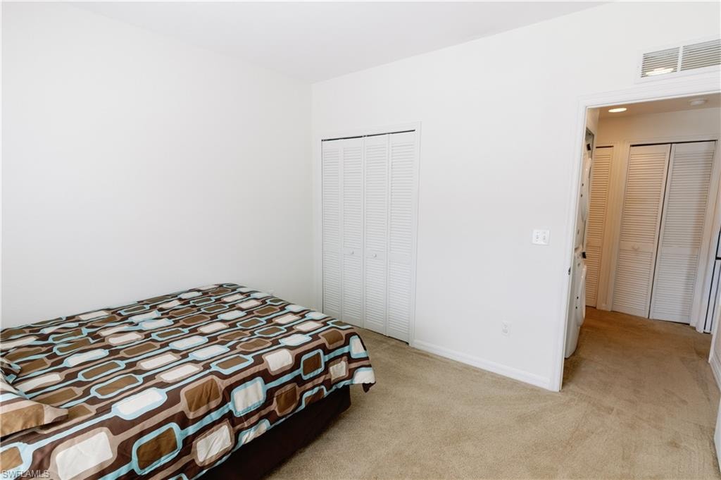 Bedroom with light carpet and a closet