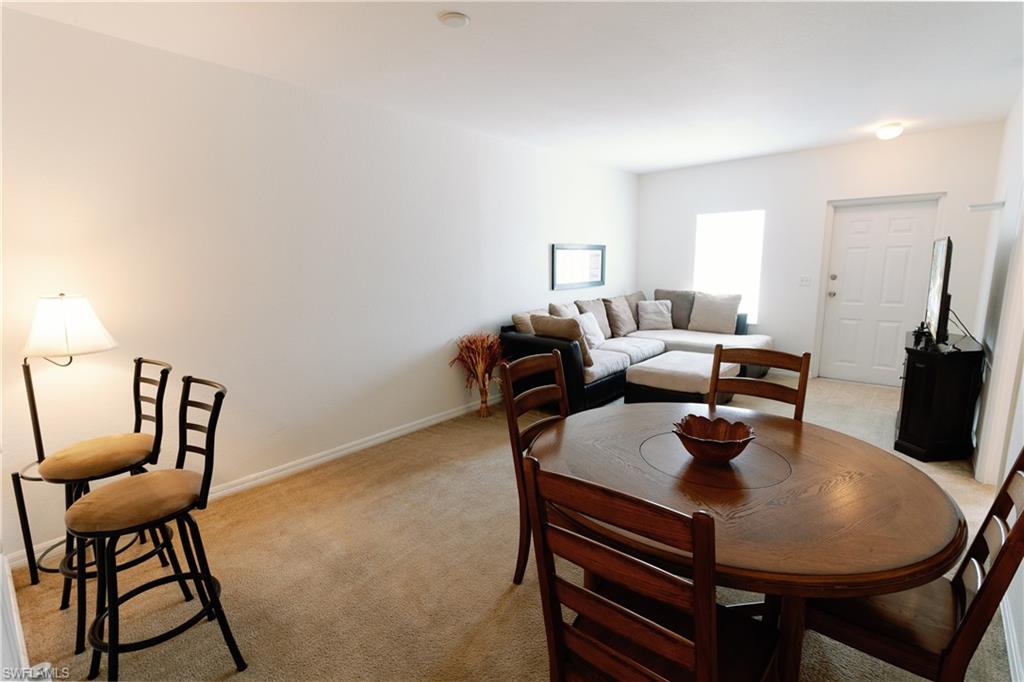 Dining space featuring light colored carpet and baseboards