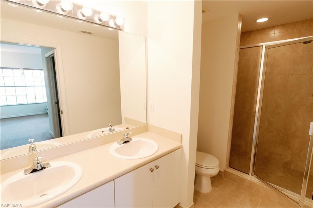 Full bath featuring light tile patterned flooring, a stall shower, and double vanity