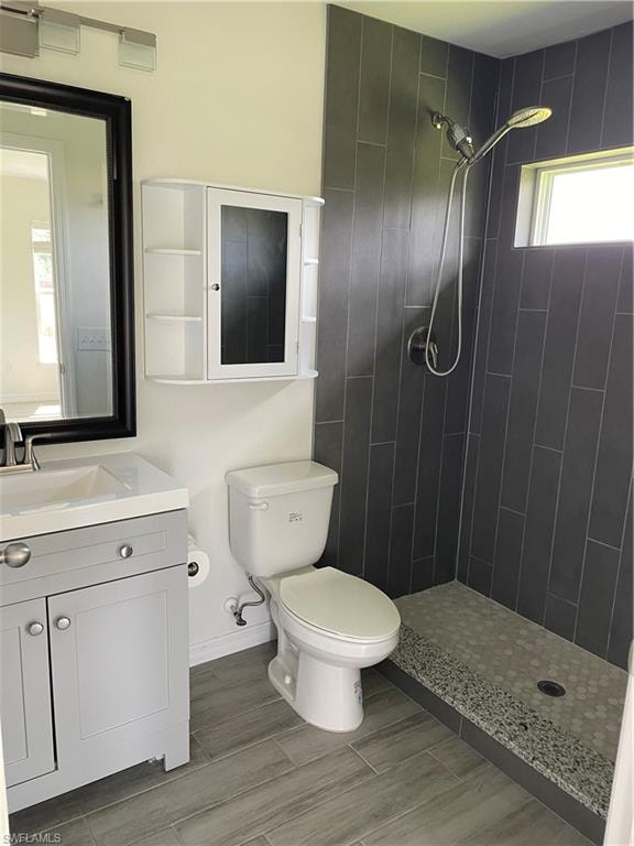 Bathroom with toilet, a tile shower, and vanity