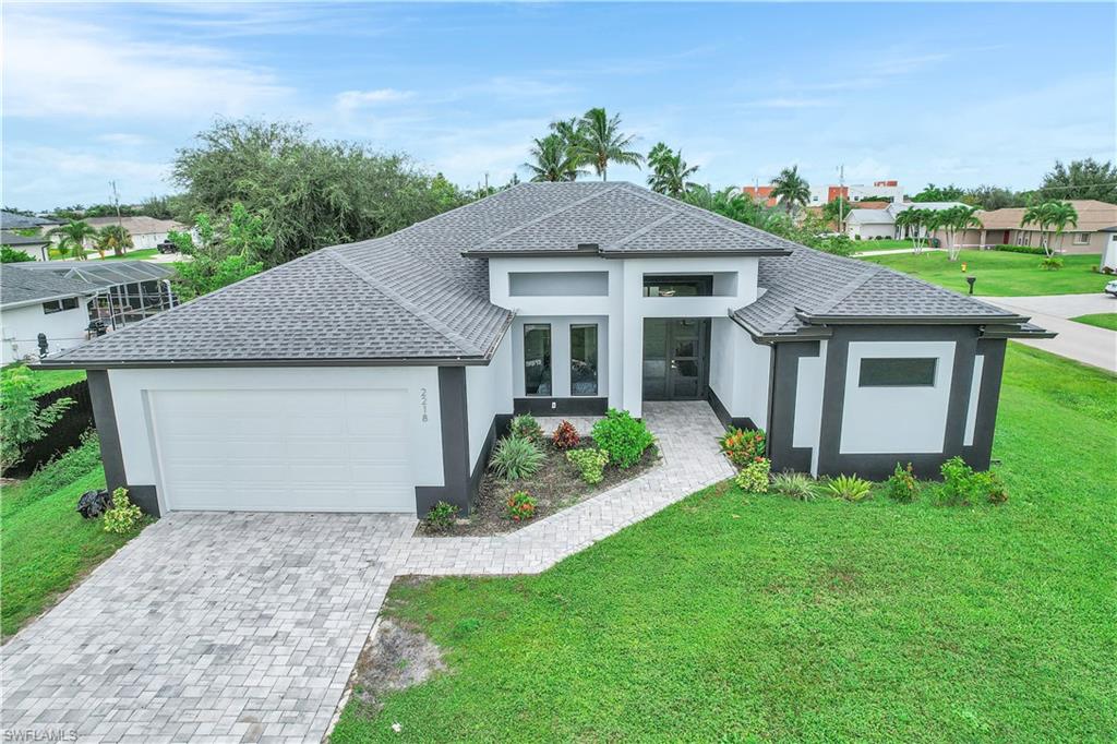 View of front of property with a front lawn, stucco siding, and decorative driveway