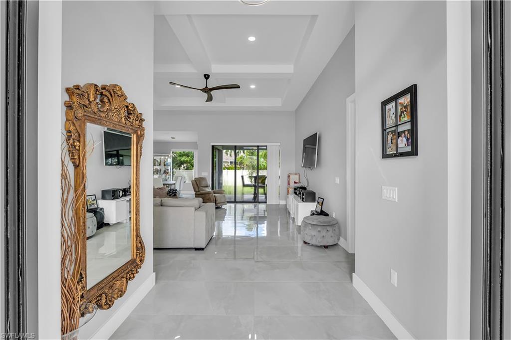 Corridor with beamed ceiling, coffered ceiling, recessed lighting, and a high ceiling