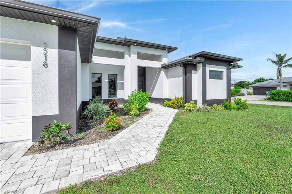 View of exterior entry with stucco siding, a yard, and a garage
