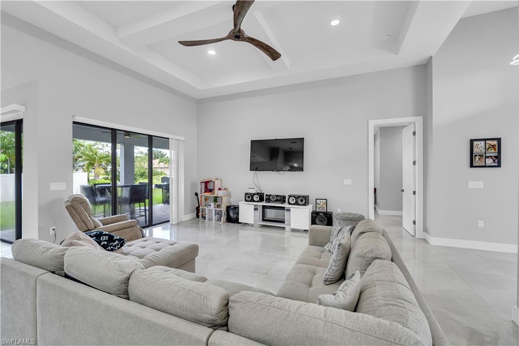 Living area featuring beamed ceiling, a high ceiling, coffered ceiling, a ceiling fan, and recessed lighting