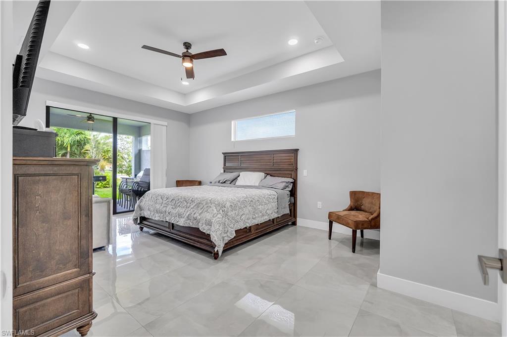Bedroom with access to exterior, a ceiling fan, a tray ceiling, and recessed lighting