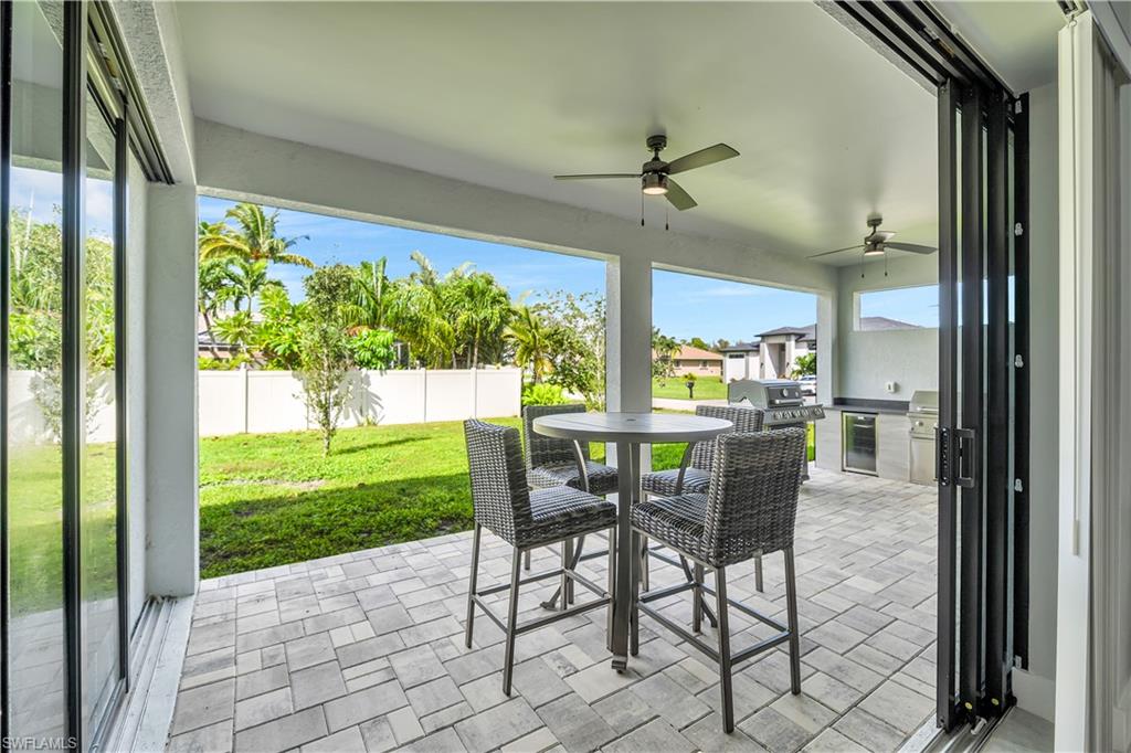 Fenced backyard featuring area for grilling, a ceiling fan, a patio area, outdoor dining area, and wine cooler