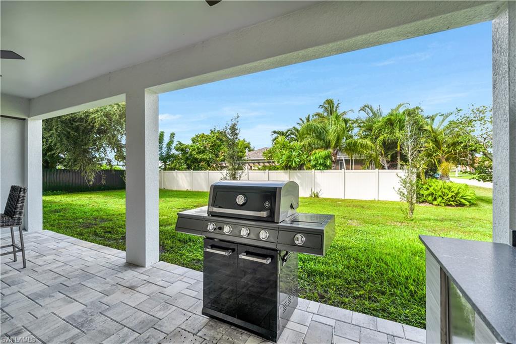 Fenced backyard with a patio, a ceiling fan, and a grill