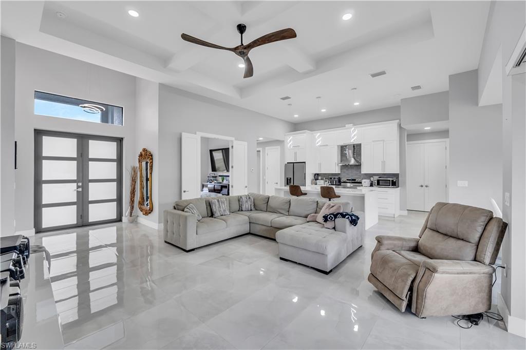 Living room featuring a ceiling fan, recessed lighting, beamed ceiling, french doors, and light marble finish flooring