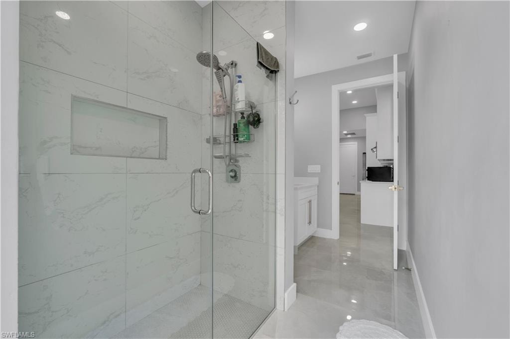 Full bath with a marble finish shower, recessed lighting, and vanity