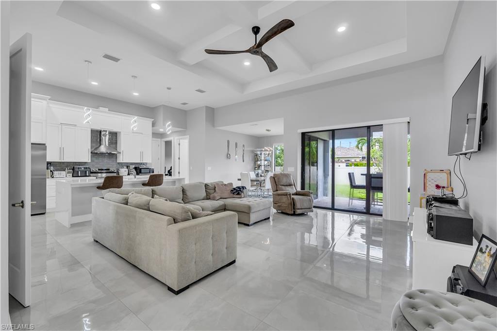 Living area with coffered ceiling, beam ceiling, recessed lighting, a ceiling fan, and a high ceiling