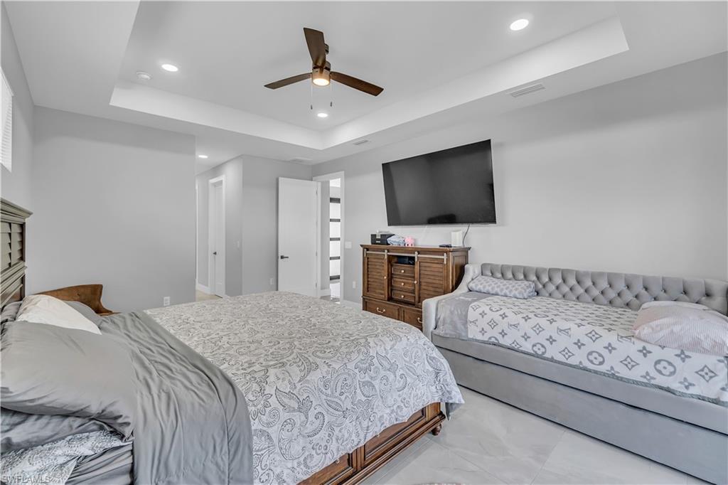 Bedroom featuring a raised ceiling, ceiling fan, and recessed lighting
