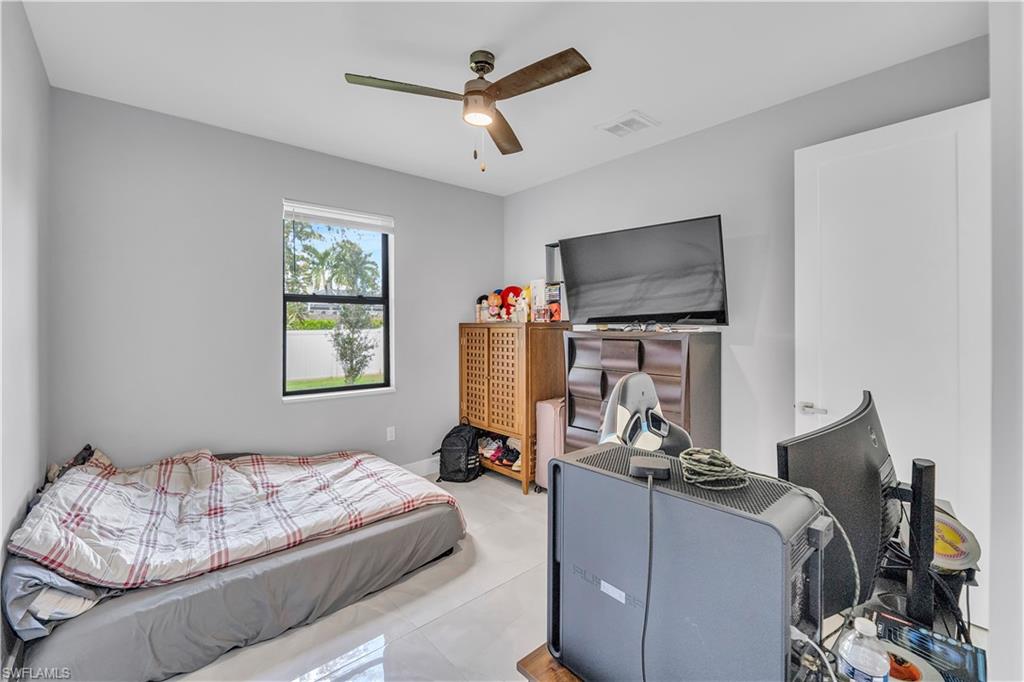 Tiled bedroom featuring ceiling fan