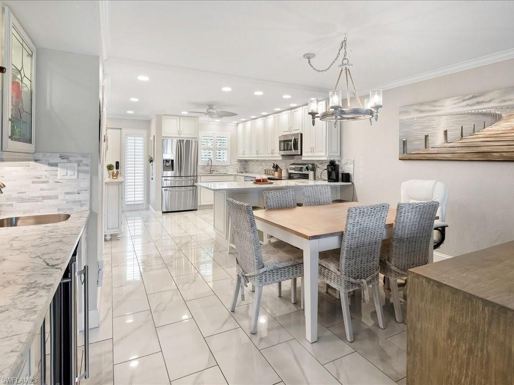 Dining room with recessed lighting, beverage cooler, ceiling fan, ornamental molding, and a chandelier