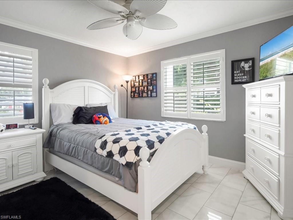 Bedroom with crown molding, a ceiling fan, and light tile patterned floors