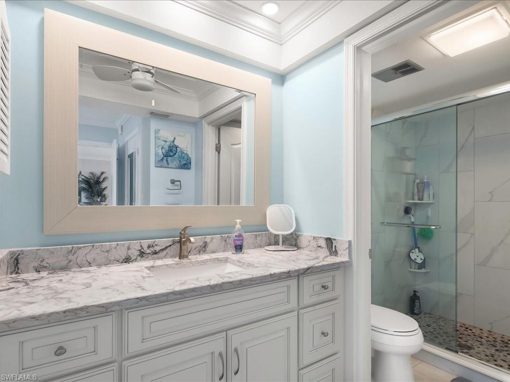 Living area featuring crown molding, light marble finish floors, a ceiling fan, and a chandelier