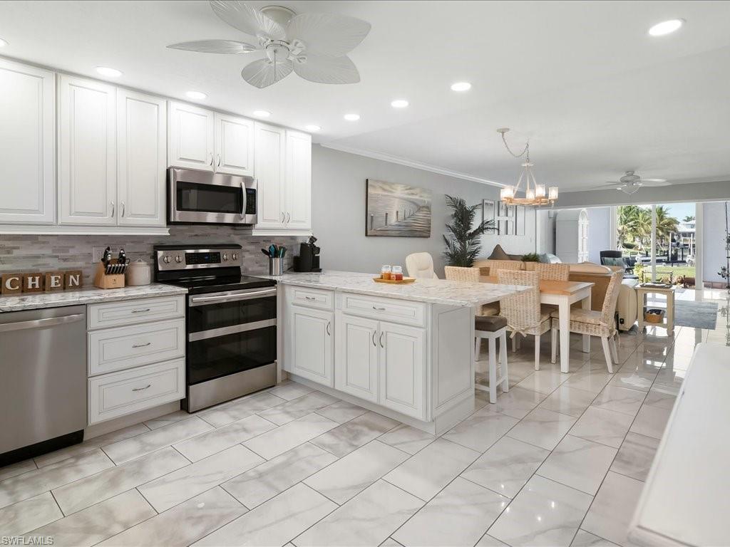 Kitchen featuring a ceiling fan, stainless steel appliances, light stone countertops, a peninsula, and recessed lighting
