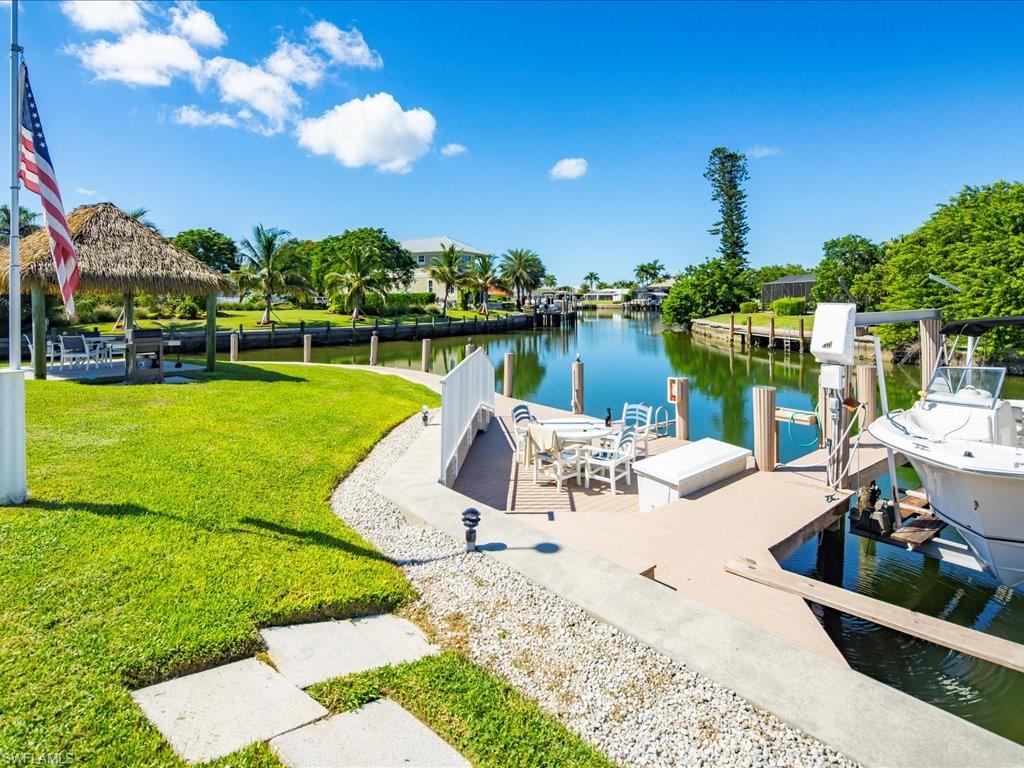 Dock area with a water view, boat lift, a lawn, and a gazebo