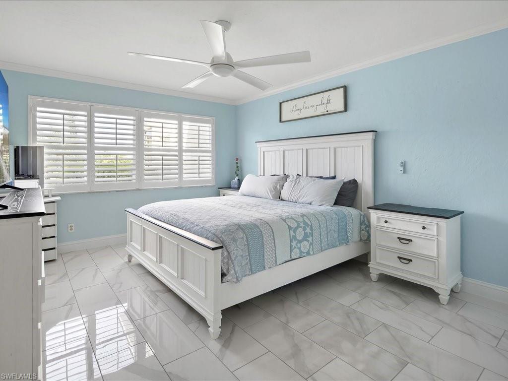 Bedroom with crown molding, a ceiling fan, and light marble finish floors