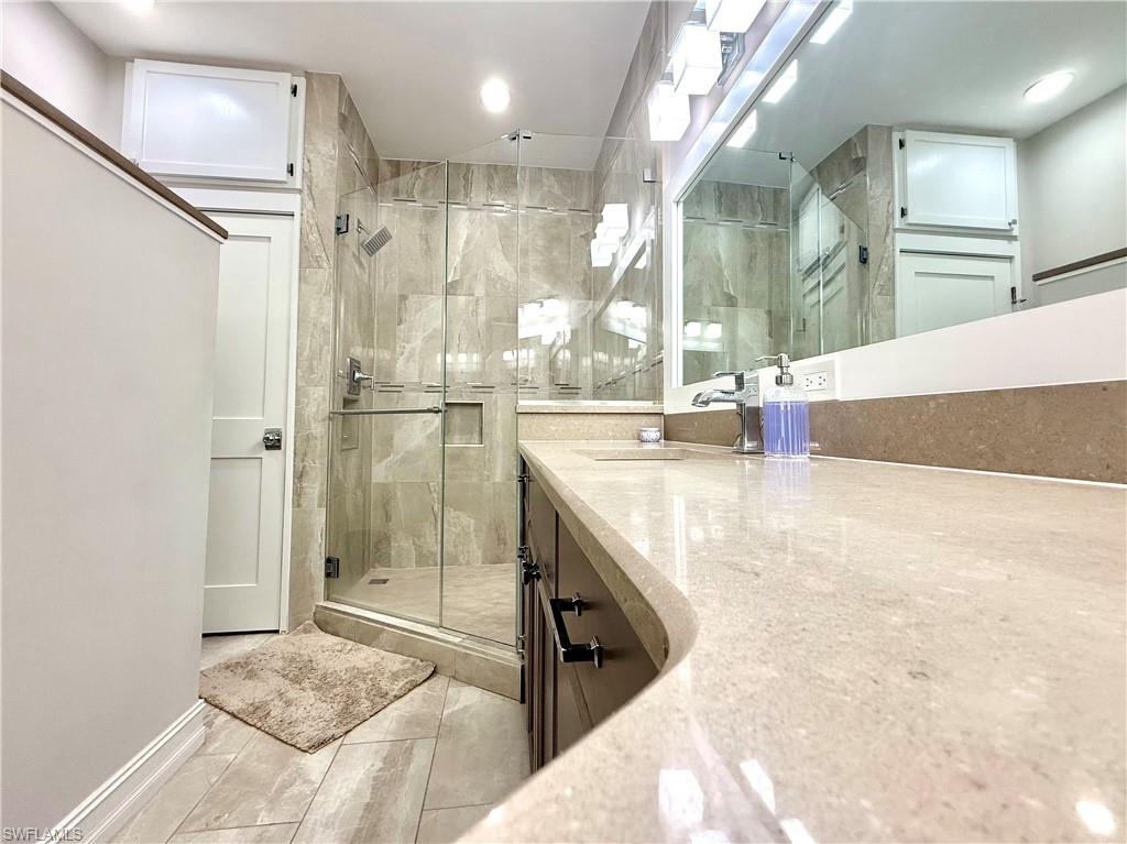 Bathroom with a shower stall, vanity, and recessed lighting