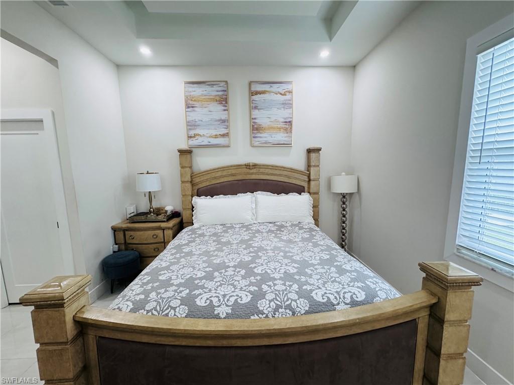 Bedroom featuring a tray ceiling, a closet, recessed lighting, and tile patterned flooring