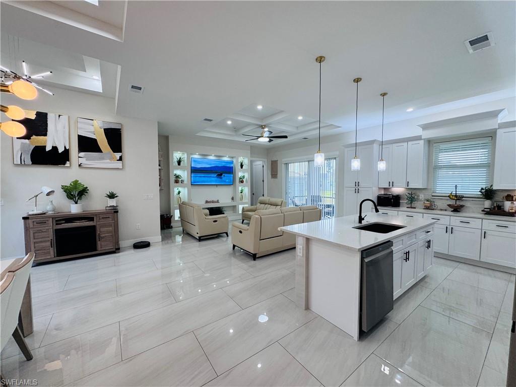 Kitchen with ceiling fan, open floor plan, decorative light fixtures, a kitchen island with sink, and white cabinetry