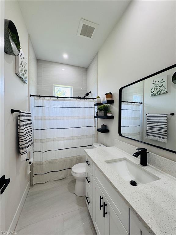 Bathroom with vanity, a shower with shower curtain, and light tile patterned floors