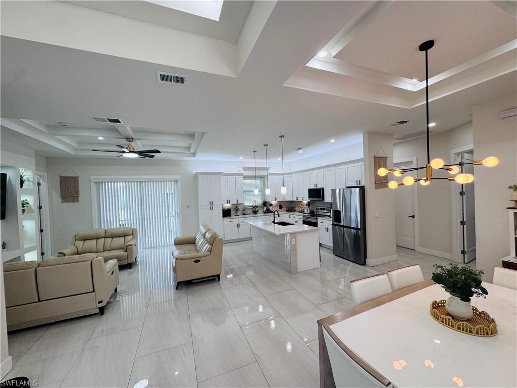 Dining area featuring a tray ceiling, ceiling fan, a chandelier, light tile patterned flooring, and recessed lighting