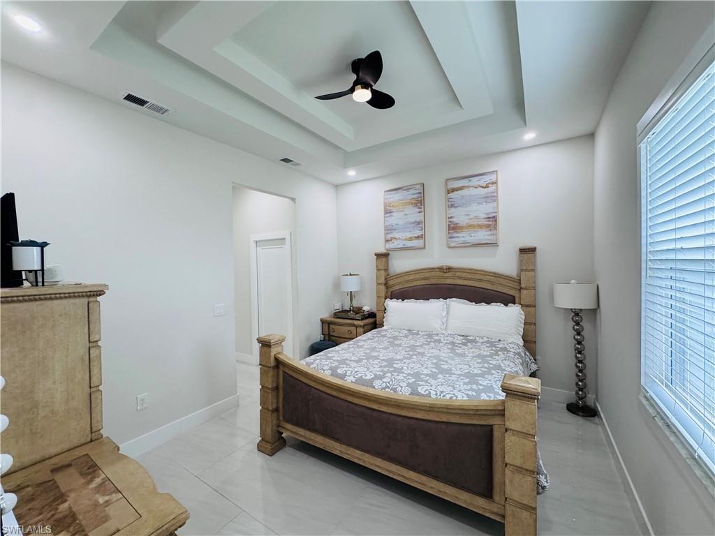Tiled bedroom with a tray ceiling and ceiling fan
